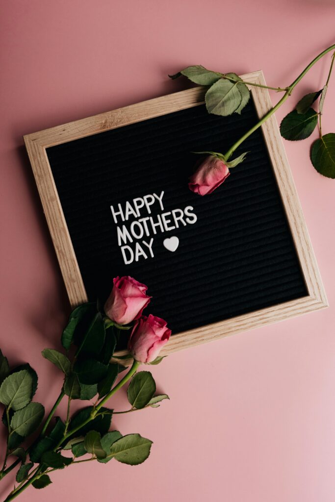 Vertical shot of a Mother's Day message on a letter board surrounded by pink roses.